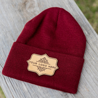 Red beanie with a gold patch on a wooden surface