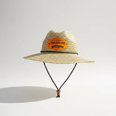 Leathering natural straw sun hat with a black cord band and chin strap, featuring an orange leather patch with custom branding.